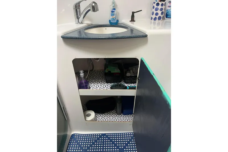 Slide: The Image of 2000 Fountaine Pajot Belize 43 bathroom sink with open storage cabinet and toiletries. - 14