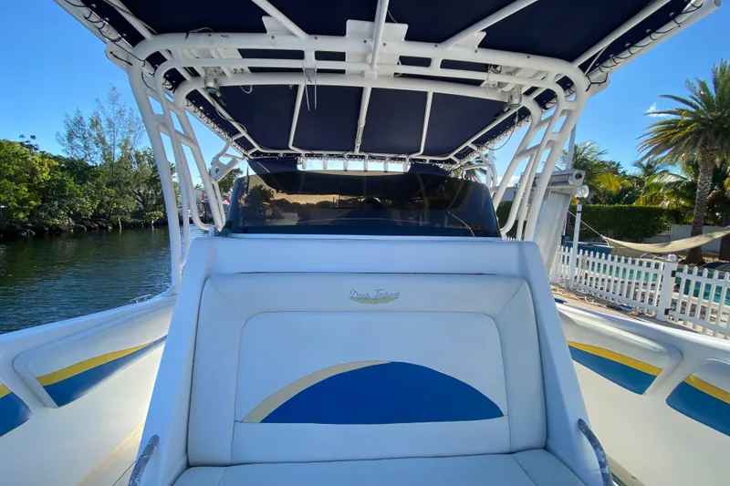 Slide: The Image of 2004 Deep Impact 36 DI boat with blue and white seating, docked near lush greenery. - 15