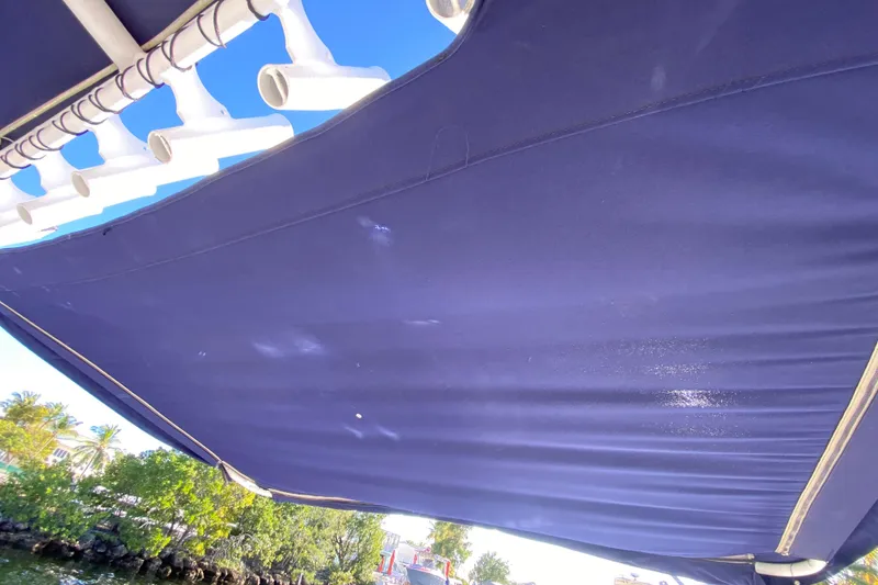 Slide: The Image of Blue canopy on a 2004 Deep Impact 36 DI boat, with rod holders and tropical scenery. - 30