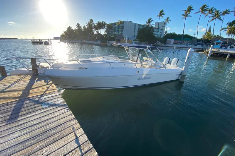 Slide: The Image of 1998 Intrepid 339 boat docked at a sunny marina with palm trees. - 11