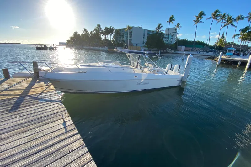 Slide: The Image of 1998 Intrepid 339 boat docked on sunny waterfront with palm trees. - 12