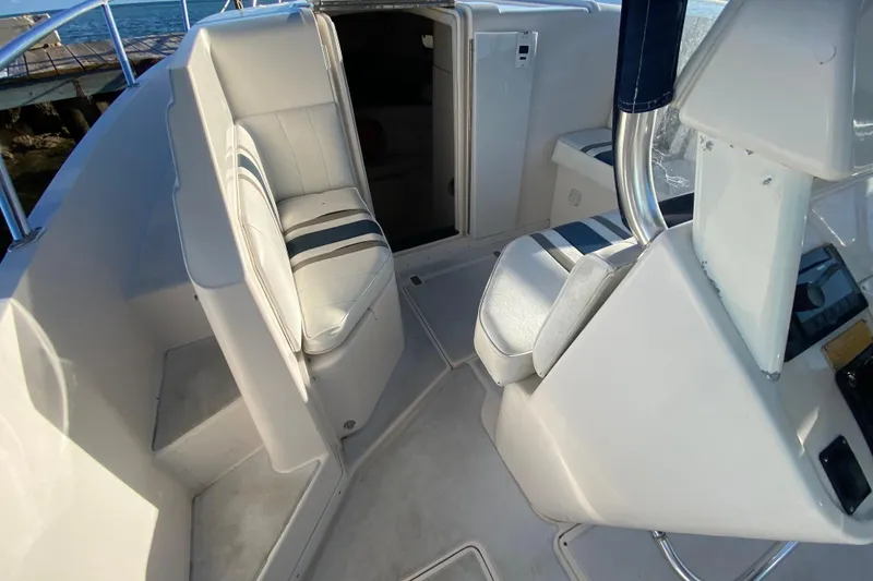 Slide: The Image of 1998 Intrepid 339 boat interior with white seating and striped cushions, near water. - 35