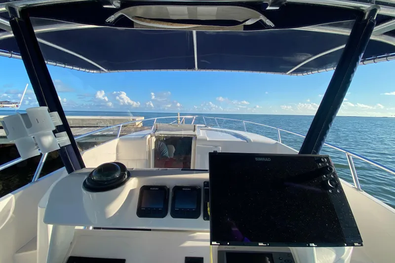 Slide: The Image of Cockpit view of 1998 Intrepid 339 boat with navigation equipment, overlooking calm ocean waters. - 45