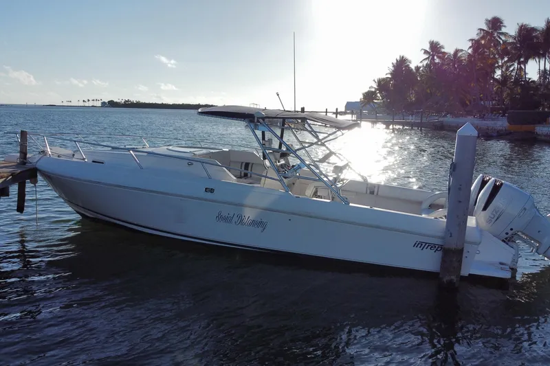 Slide: The Image of 1998 Intrepid 339 boat docked by palm trees at sunset. - 8