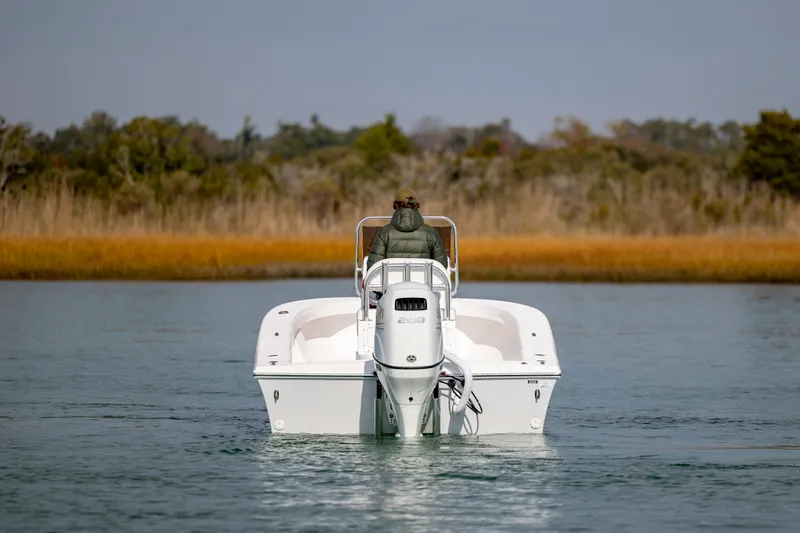 Slide: The Image of 2026 Privateer ROAMER II boat on calm water, person steering, scenic background. - 2