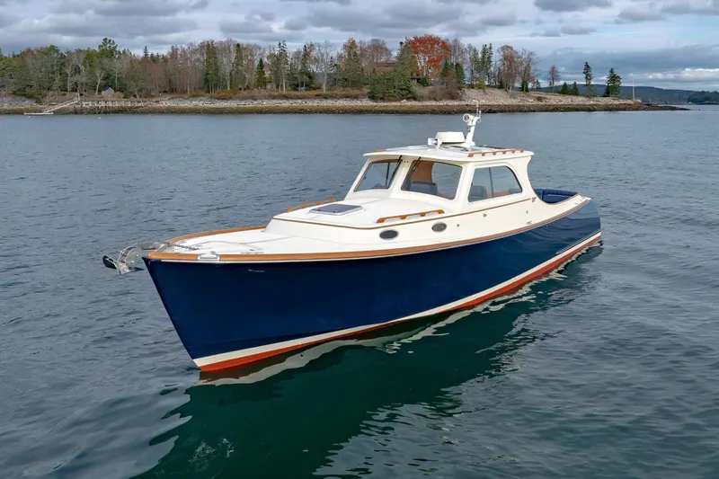 Slide: The Image of 2003 Hinckley Picnic Boat EP cruising on calm waters near a wooded shoreline. - 1