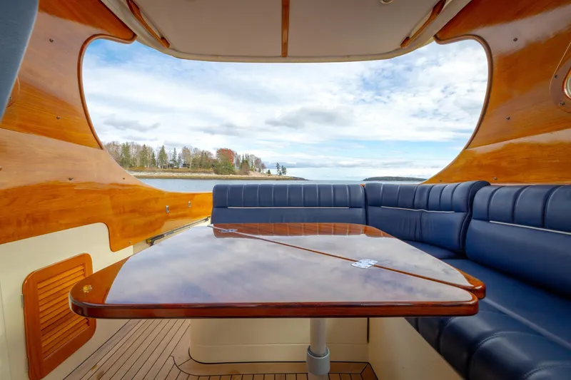 Slide: The Image of Interior of 2003 Hinckley Picnic Boat EP with wooden table and blue seating, overlooking scenic water view. - 28