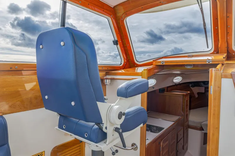 Slide: The Image of 2003 Hinckley Picnic Boat EP interior with blue captain's chair and wooden cabin details. - 33