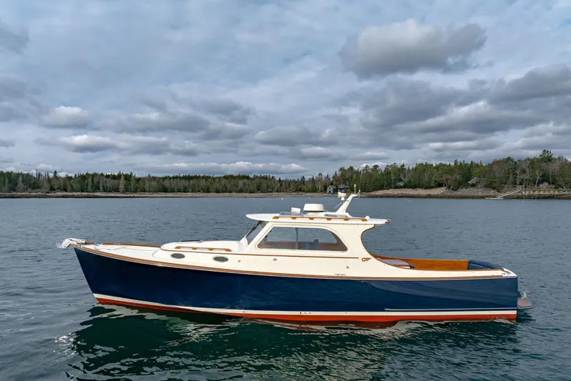 Slide: The Image of 2003 Hinckley Picnic Boat EP on calm water, cloudy sky, forested shoreline. - 4