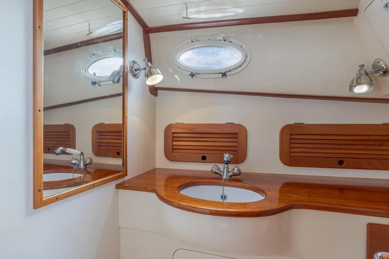 Slide: The Image of 2003 Hinckley Picnic Boat EP bathroom with wooden accents and oval porthole window. - 44