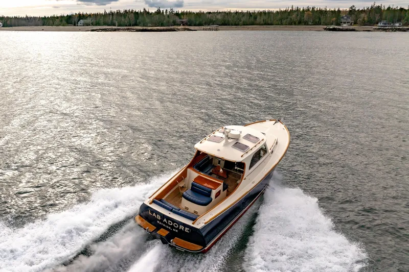 Slide: The Image of 2003 Hinckley Picnic Boat EP cruising on a scenic lake with forested shoreline. - 11