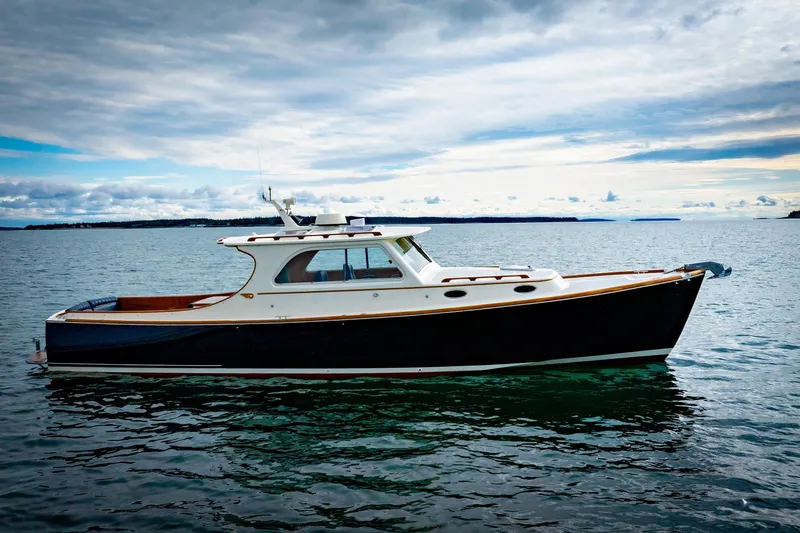 Slide: The Image of 2003 Hinckley Picnic Boat EP on calm water under cloudy sky. - 2