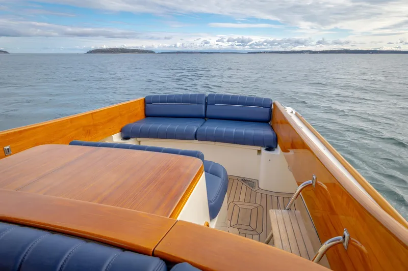 Slide: The Image of 2003 Hinckley Picnic Boat EP with blue seating and wooden deck on open water. - 21