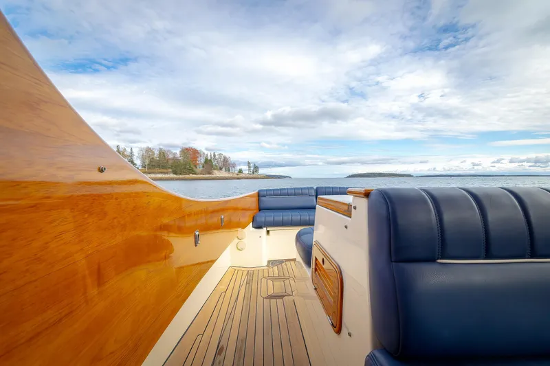 Slide: The Image of 2003 Hinckley Picnic Boat EP interior with blue seating and wooden accents on open water. - 24