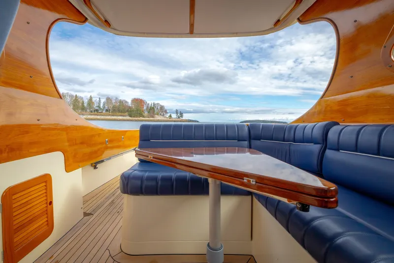 Slide: The Image of Interior of 2003 Hinckley Picnic Boat EP with blue seating and wooden accents, overlooking scenic water. - 29