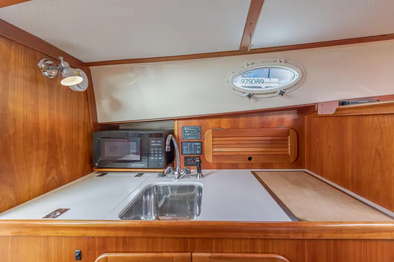 Slide: The Image of 2003 Hinckley Picnic Boat EP interior kitchen with sink, microwave, and wooden cabinetry. - 36