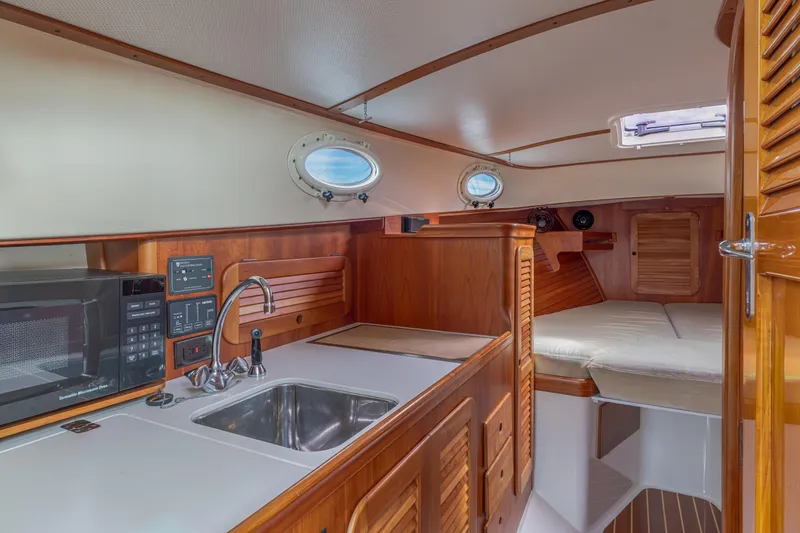 Slide: The Image of 2003 Hinckley Picnic Boat EP interior with kitchenette, sink, and cozy sleeping area. - 37