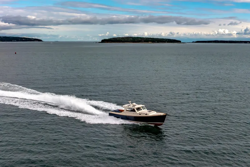 Slide: The Image of 2003 Hinckley Picnic Boat EP cruising on open water under a cloudy sky. - 5