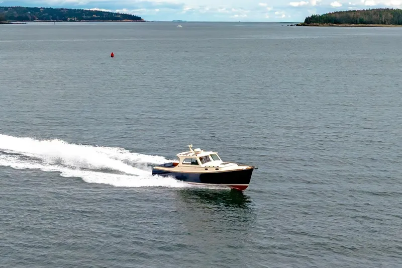 Slide: The Image of 2003 Hinckley Picnic Boat EP cruising on open water with scenic coastline. - 6