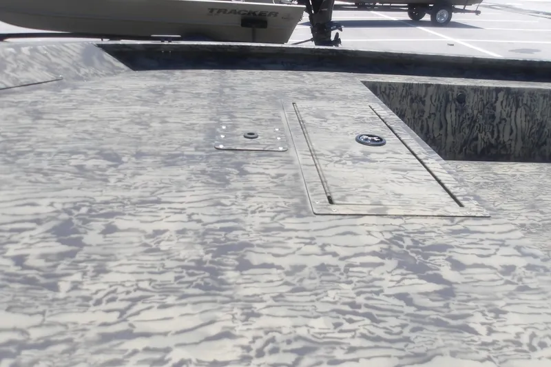 Slide: The Image of 2026 Tracker Grizzly 1648 SC boat deck with camouflage pattern in a parking lot. - 10