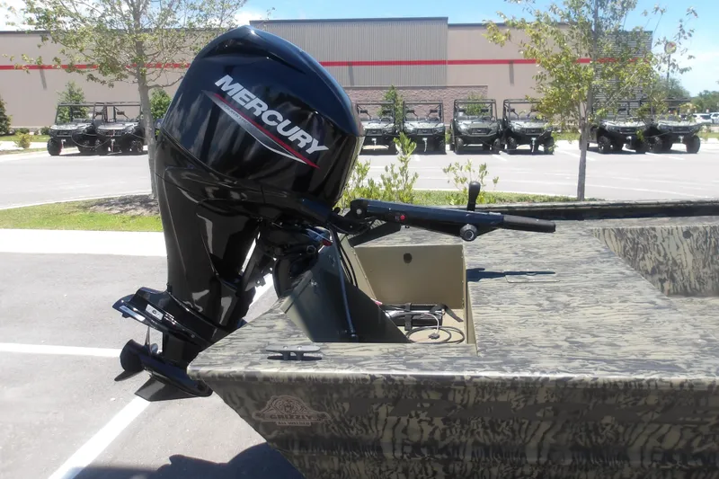 Slide: The Image of 2026 Tracker Grizzly 1648 SC boat with Mercury outboard motor in parking lot. - 2