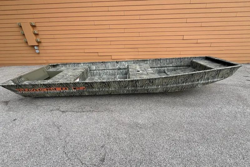 The Image of 2026 Tracker Grizzly 15 Jon boat with camouflage design, parked on pavement. - 0