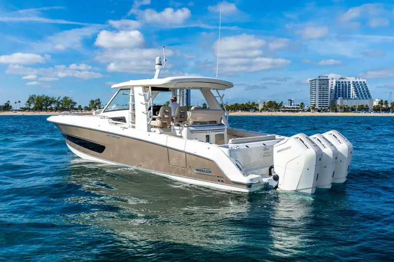 Slide: The Image of 2024 Boston Whaler 420 Outrage boat cruising on blue ocean near city skyline. - 10