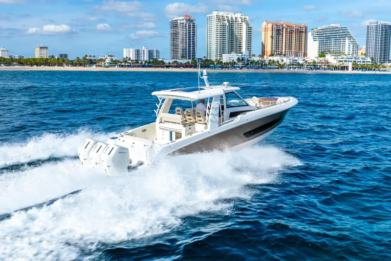 Slide: The Image of 2024 Boston Whaler 420 Outrage cruising near a city skyline on a sunny day. - 20