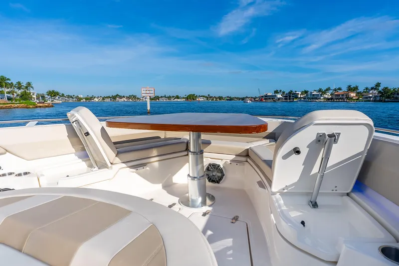 Slide: The Image of 2024 Boston Whaler 420 Outrage boat interior with seating and table, overlooking scenic waterfront. - 26