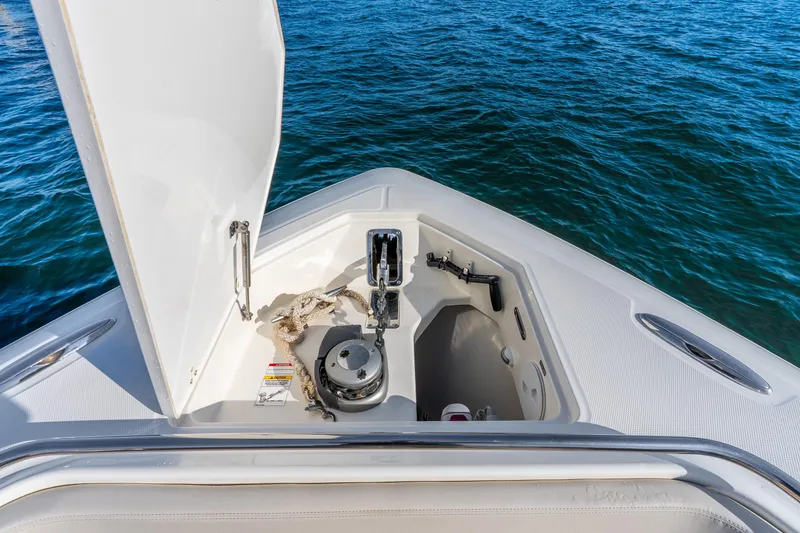 Slide: The Image of 2024 Boston Whaler 420 Outrage anchor compartment with open hatch, on calm blue water. - 28