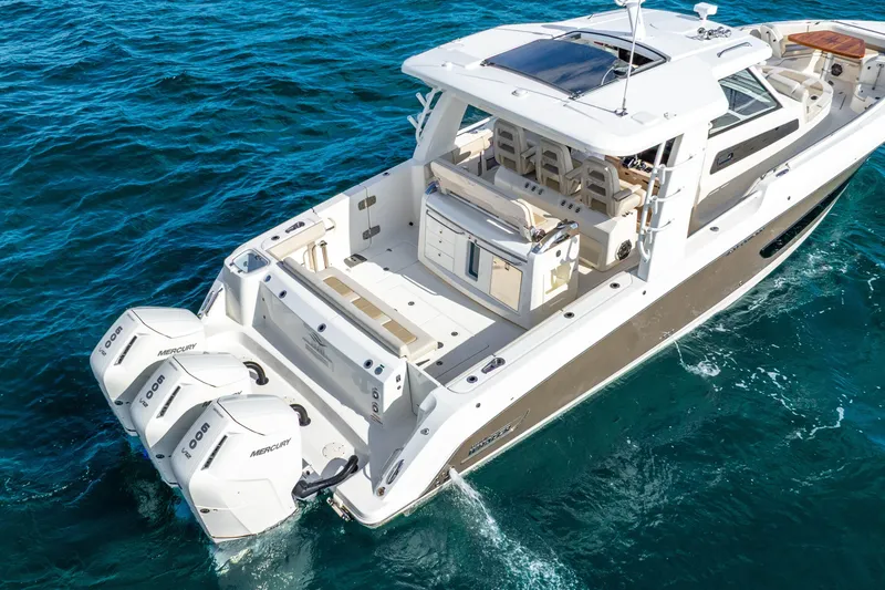 Slide: The Image of 2024 Boston Whaler 420 Outrage boat with triple Mercury engines on blue ocean water. - 4