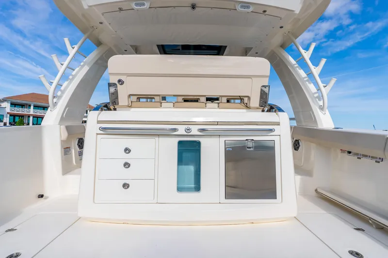 Slide: The Image of 2024 Boston Whaler 420 Outrage boat interior with storage and seating under clear blue sky. - 43