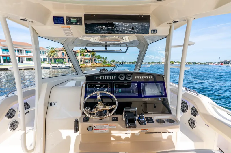Slide: The Image of 2024 Boston Whaler 420 Outrage helm with advanced navigation system, docked near waterfront homes. - 45