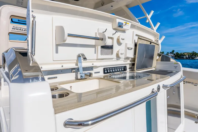 Slide: The Image of 2024 Boston Whaler 420 Outrage boat kitchen area with sink and storage compartments. - 50
