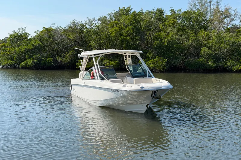 Slide: The Image of 2018 Boston Whaler 270 Vantage boat cruising on a calm river with lush greenery. - 2