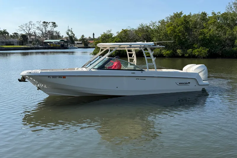 Slide: The Image of 2018 Boston Whaler 270 Vantage boat on calm water, surrounded by greenery. - 5