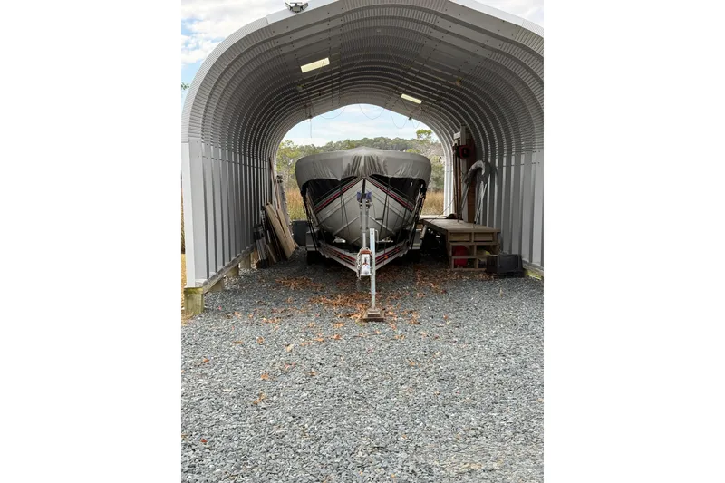 Slide: The Image of 1988 Thunderbird Formula 311 SR1 boat stored in a metal shelter on gravel. - 11
