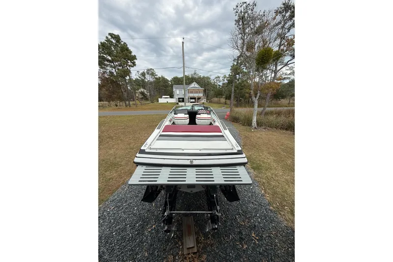 Slide: The Image of 1988 Thunderbird Formula 311 SR1 boat on gravel driveway, surrounded by trees and cloudy sky. - 4