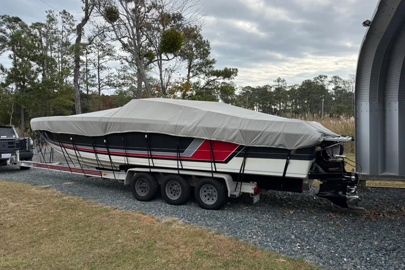 Slide: The Image of 1988 Thunderbird Formula 311 SR1 boat covered on a trailer, parked outdoors. - 9