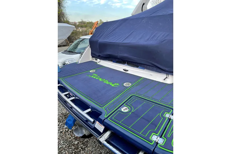 Slide: The Image of 2018 Chaparral 287 SSX boat with custom blue and green deck cover, parked outdoors. - 4