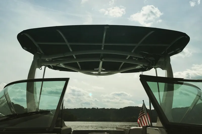 Slide: The Image of 2018 Chaparral 287 SSX boat with canopy, American flag, and scenic lake view. - 7