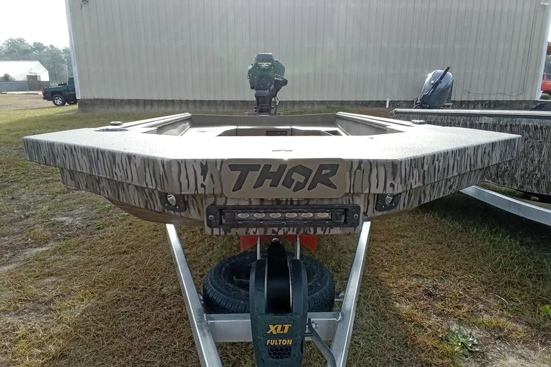 Slide: The Image of 2026 Thor 1754 Swamp Hammer boat on trailer, camo design, outdoor setting. - 15