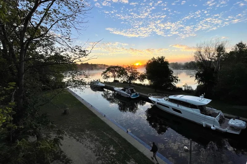 Slide: The Image of Sunrise over a serene river with a 2017 Prestige 500S yacht docked. - 2