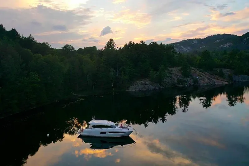 Slide: The Image of Prestige 500S yacht on serene lake at sunset, surrounded by lush forest, 2017 model. - 3