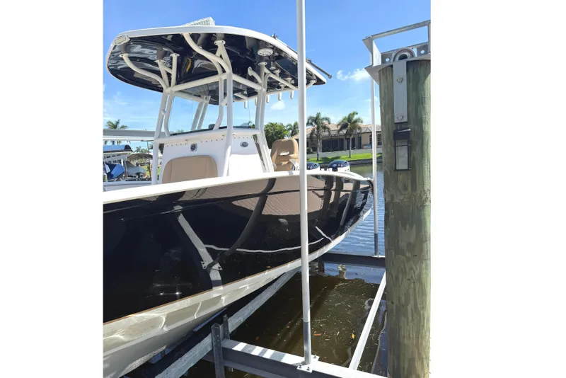 Slide: The Image of 2019 Cape Horn 27XS boat docked, featuring sleek black hull and T-top, under clear blue sky. - 4