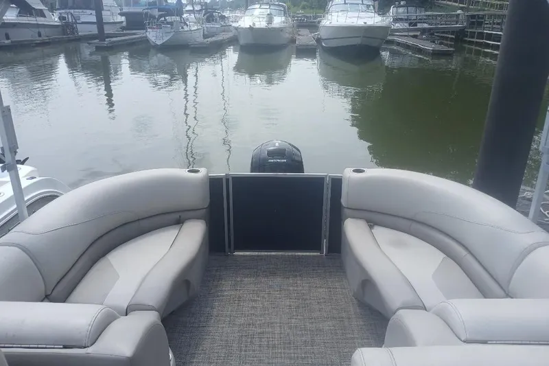 Slide: The Image of 2023 Cypress Cay Seabreeze 232 pontoon boat interior at marina, featuring plush seating. - 11