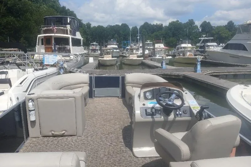 Slide: The Image of 2023 Cypress Cay Seabreeze 232 pontoon boat docked at a marina, surrounded by other boats. - 5