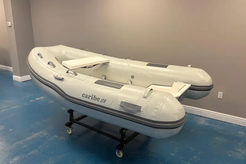 Slide: The Image of 2024 Caribe L-9 inflatable boat displayed indoors with wooden flooring and decorative plants. - 3