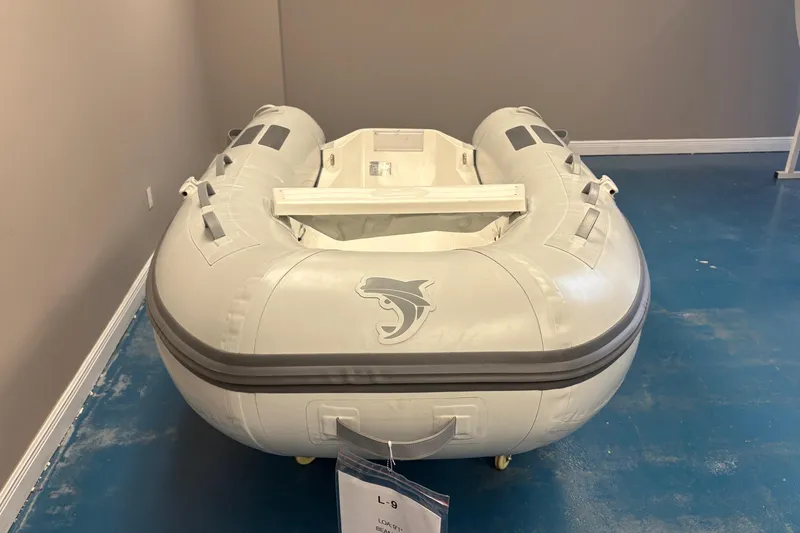 Slide: The Image of 2024 Caribe L-9 inflatable boat displayed indoors with outboard motor nearby. - 4