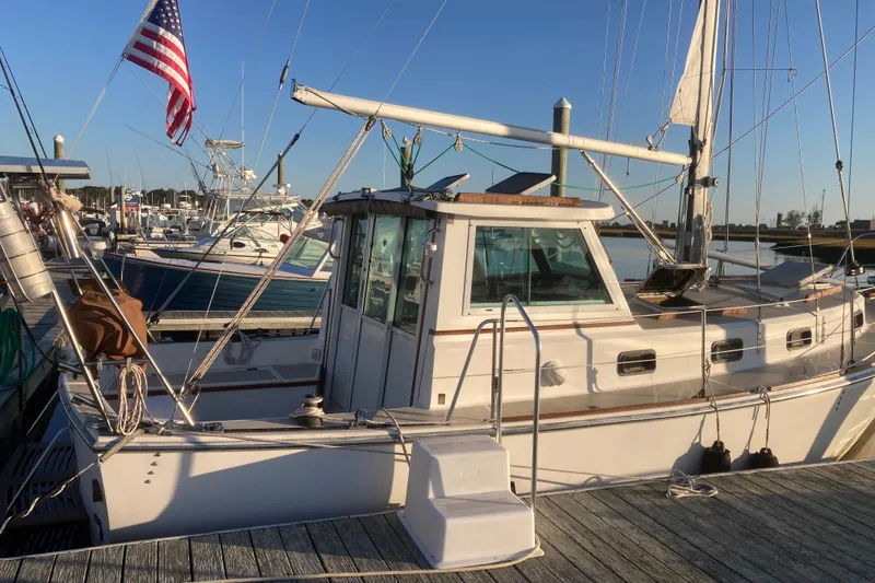 The Image of 1989 Cape Dory 300 Motorsailer docked, featuring classic design and American flag. - 1